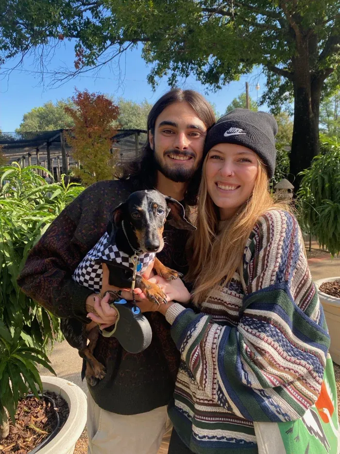 A smiling couple holding their dachshund